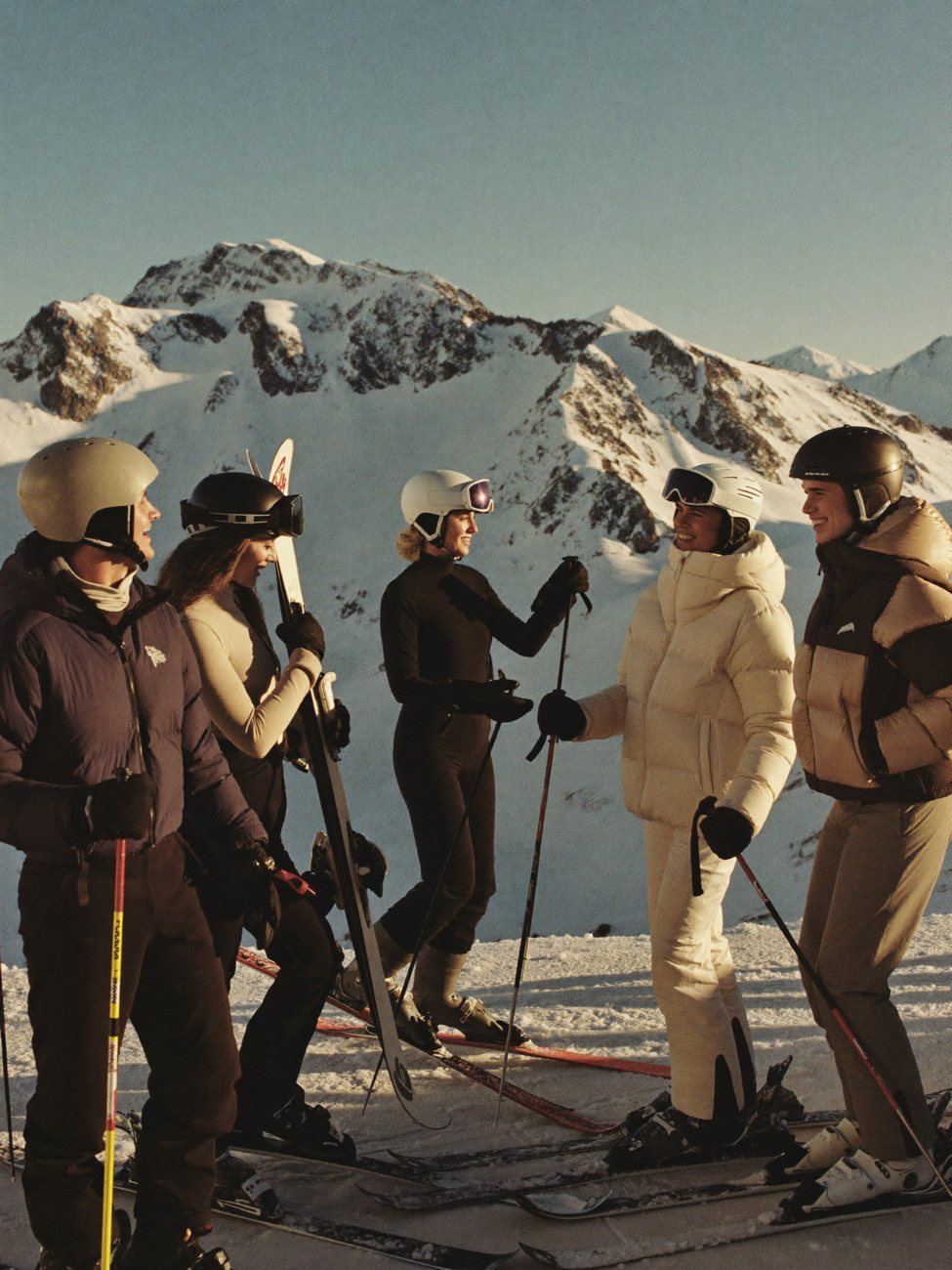 A group of skiers in helmets at the top of a sunlit run