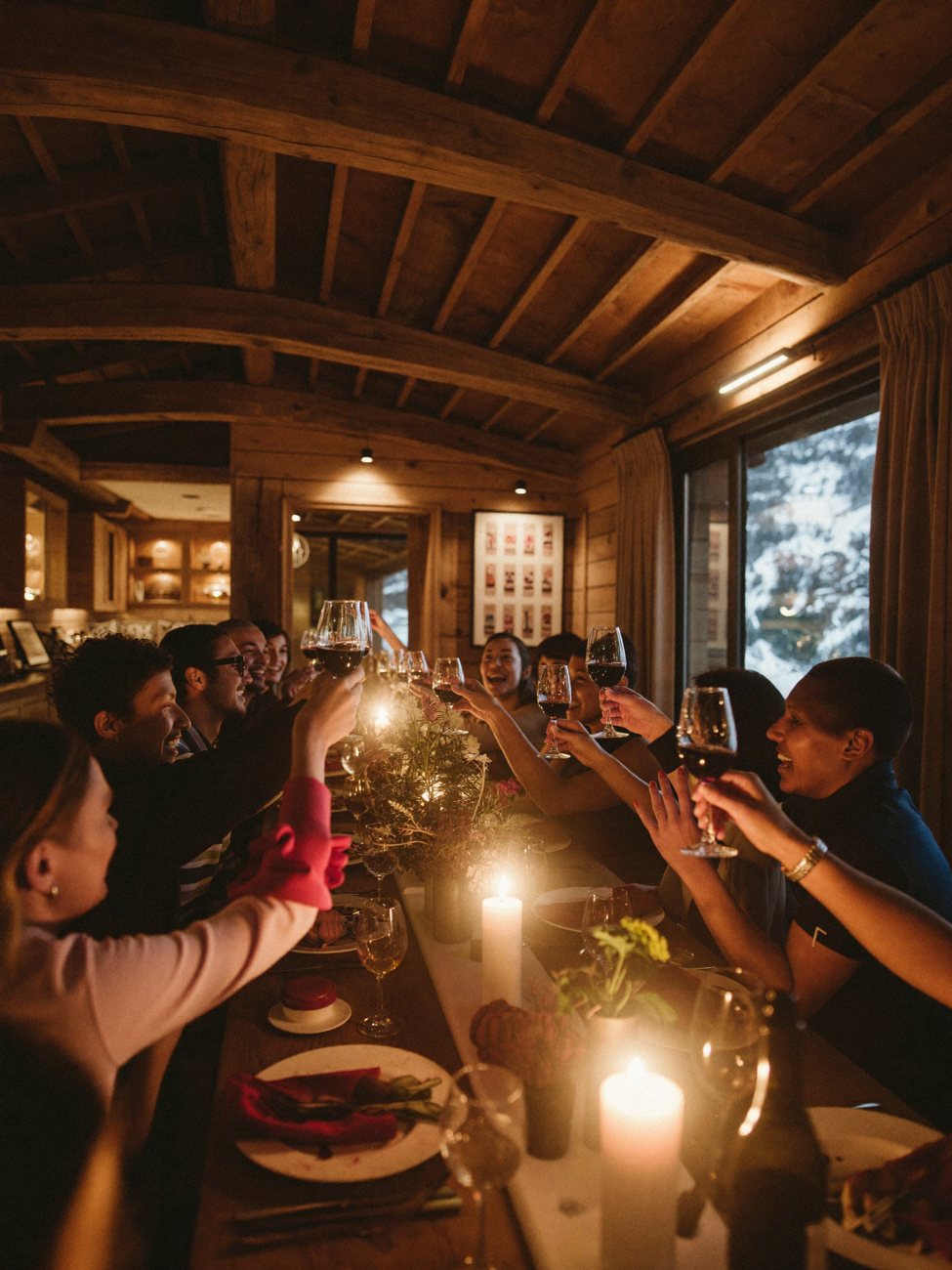 A group at a candlelit dinner inside a luxury alpine chalet